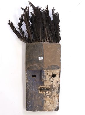 un masque en bois dont le visage est orné de plumes