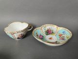 two cups and saucers with floral designs on them on a table