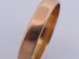 a close up of a gold wedding ring on a white background