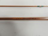 two wooden fishing rods with a green handle on a white surface