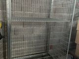 une grande cage métallique munie de roues, dans une pièce