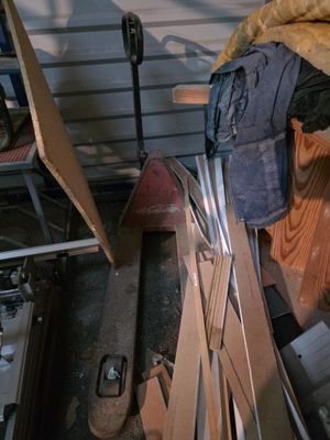un tas de bric-à-brac dans un garage, à côté d'un tas de bois