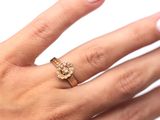 La main de la femme tient une bague en or sertie d'un diamant au centre.