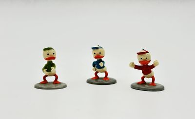 trois figurines de trois personnages différents sur une surface blanche