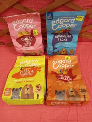 trois sacs de croquettes pour chien posés les uns à côté des autres sur un lit