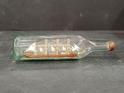 une bouteille en verre contenant un bateau, posée sur une table