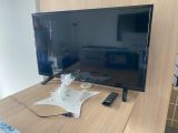 une télévision à écran plat posée sur un bureau, avec une télécommande