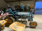 un tracteur bleu et une brouette jaune dans un garage