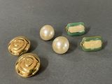 three gold and green buttons and two pearls on a table