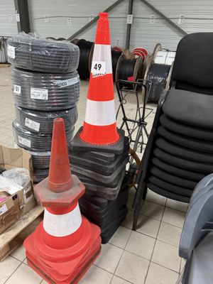 a pile of orange and white traffic cones next to a pile of black and white tires