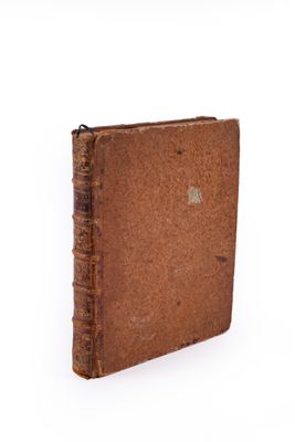 un vieux livre à la couverture brune posé sur une surface blanche