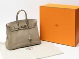the hermes bag is sitting next to an orange box