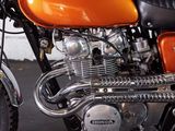 an orange motorcycle parked in a garage with a brick wall in the background
