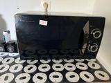 un micro-ondes noir posé sur une cuisinière