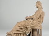 a statue of a woman sitting on a bench with her legs crossed