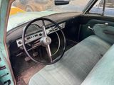 steering wheel and dashboard of an old green car in a parking lot