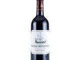 the bottle of red wine is sitting on a white surface