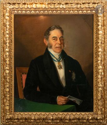 portrait d'un homme en costume noir et cravate, assis à une table