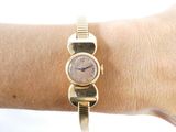 a woman ' s wrist that has a gold watch on it