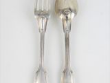 deux cuillères et une fourchette sur une surface blanche