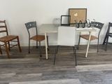 plusieurs chaises et une table dans une pièce où est accroché un tableau au mur