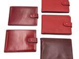 un lot de quatre portefeuilles en cuir rouge et marron sur fond blanc