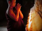 man praying in front of a candle in a dark room