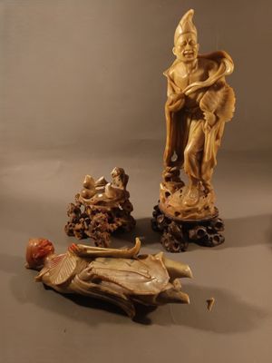une statue représentant un homme assis sur un rocher, à côté d'autres statues