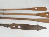 three old wooden paddles and a knife on a white surface