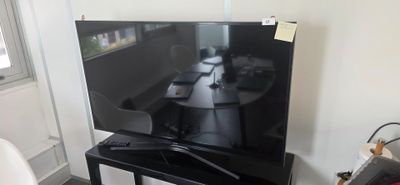 un téléviseur à écran plat posé sur un support dans le coin d'une pièce