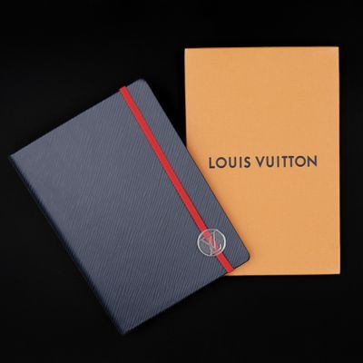 a louis vuitton notebook with a red stripe on the cover