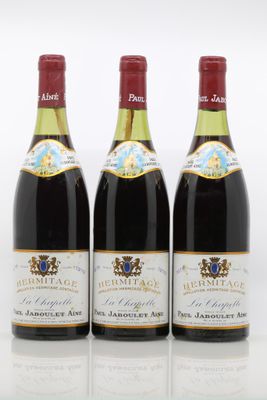 trois bouteilles de vin posées les unes à côté des autres sur une surface blanche