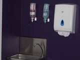 une salle de bains violette équipée d'un lavabo et d'un sèche-mains