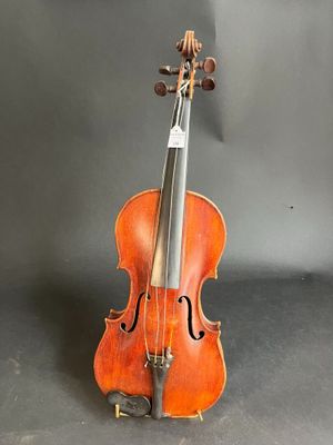 an old violin sits on a stand against a gray background