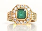 an emerald and diamond ring on a white surface