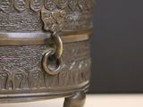 an antique brass planter on a table with a black background
