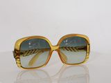 sunglasses on a white surface with a reflection of the sun in the lens