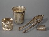 une tasse en argent, une cuillère et un repose-cuillère posés sur une table