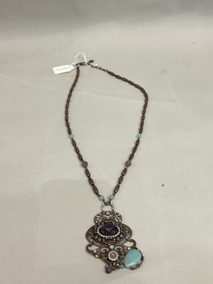 a close up of a necklace on a table with a tag