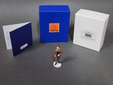 a small figurine of a man standing in front of a blue box
