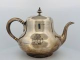 an antique silver teapot with a monogram on the lid