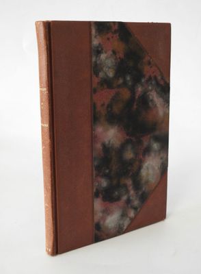 an old book with a brown cover sitting on top of a white table