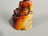 an image of a small statue of a person sitting on a rock