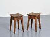 two small wooden stools sitting on top of a cement floor