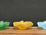three different colored plastic flowers sitting on top of a wooden table