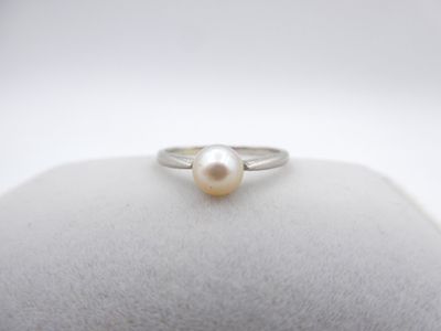 a white pearl ring sitting on top of a white cushion