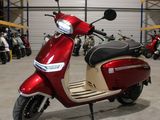 un scooter rouge garé dans un entrepôt, avec d'autres scooters en arrière-plan