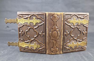 brass plated book with ornate design on it on a gray surface