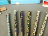 several pens are lined up on a table with a box of matches