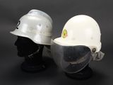 pair of white hard hats with face shields on display against a black background